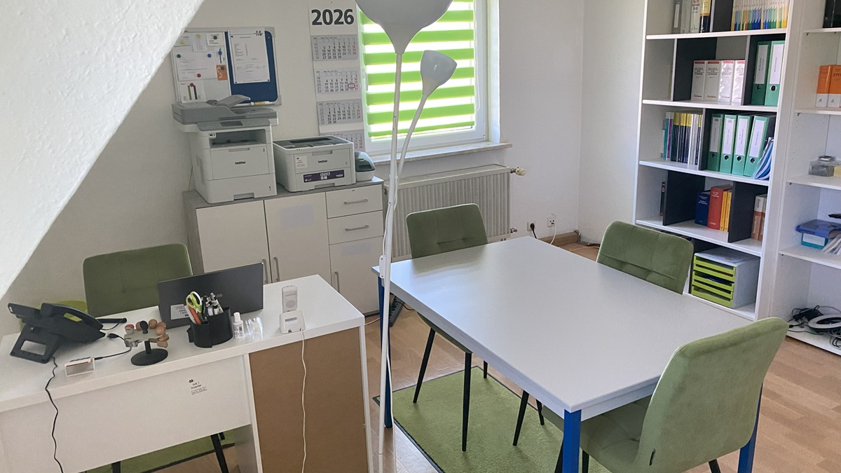 Büroraum mit Regal, Besprechungstisch und Arbeitsplatz